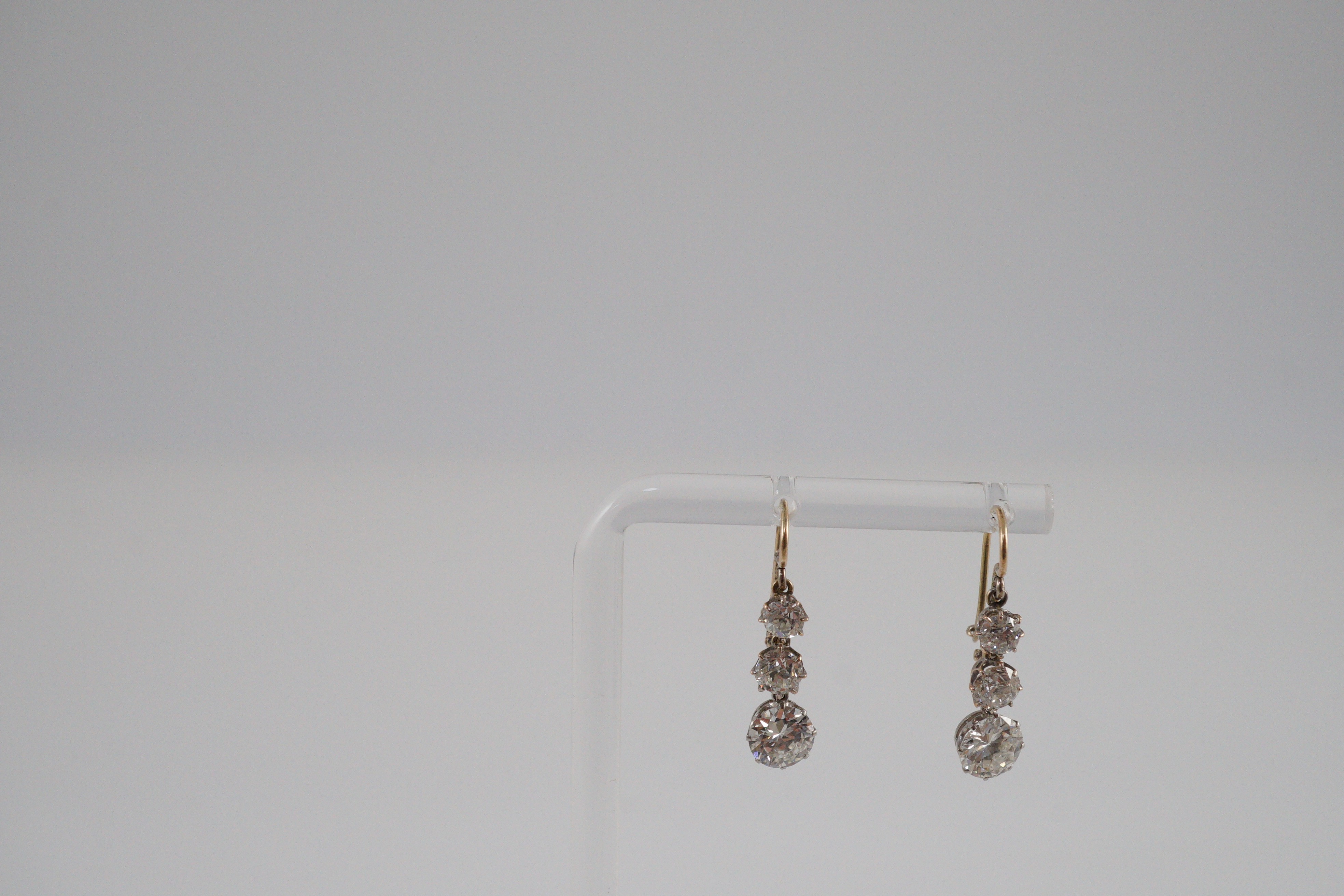 A pair of early to mid 20th century gold, platinum and graduated three stone diamond set drop earrings